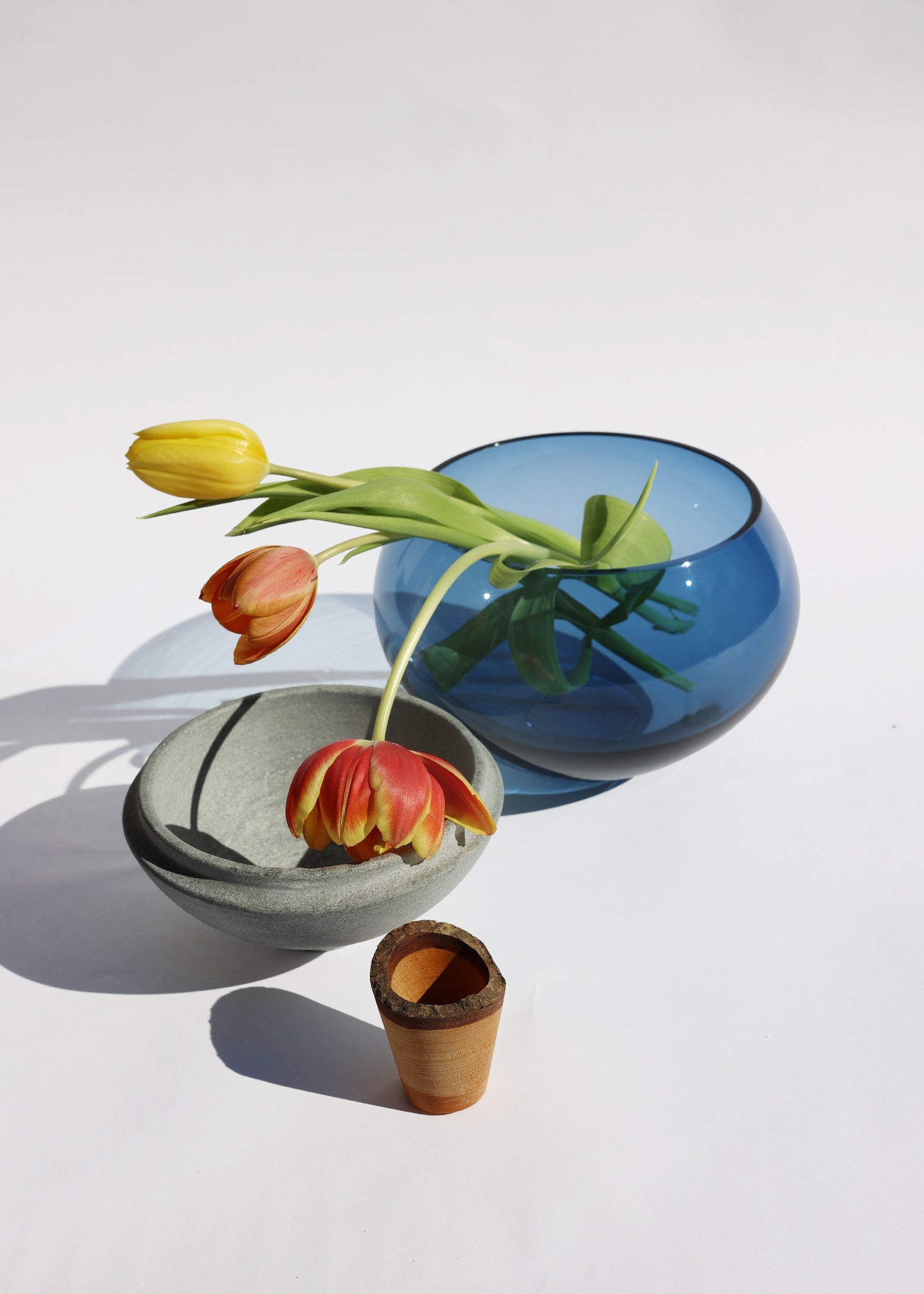 Istanbul Stacking Vessel in blue and soapstone unstacked with flowers, combining smooth lines and refined craftsmanship.