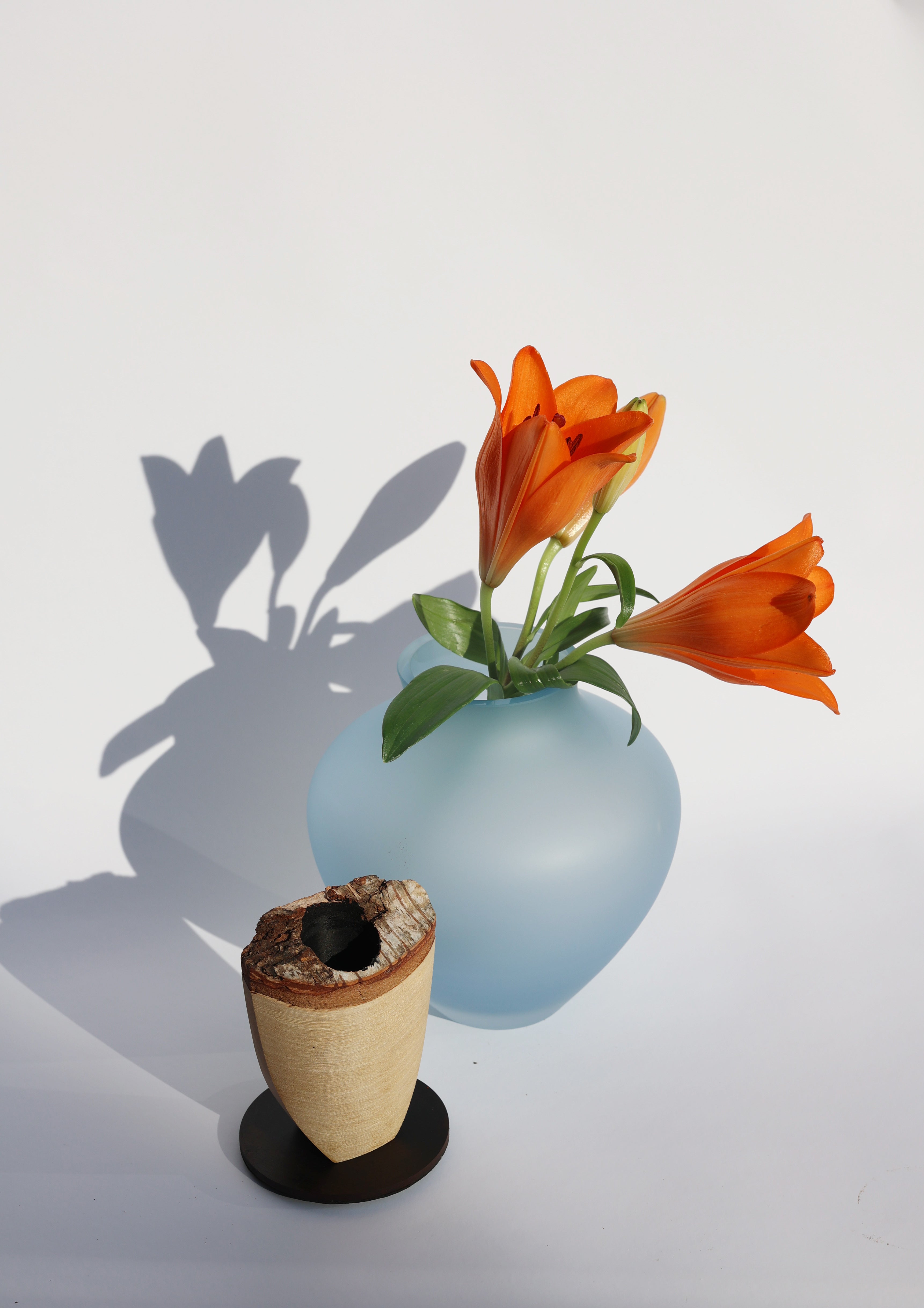 Ohana Stacking Vessel in Blue Satin unstacked wit lily, showcasing its elegant layered design and smooth texture.