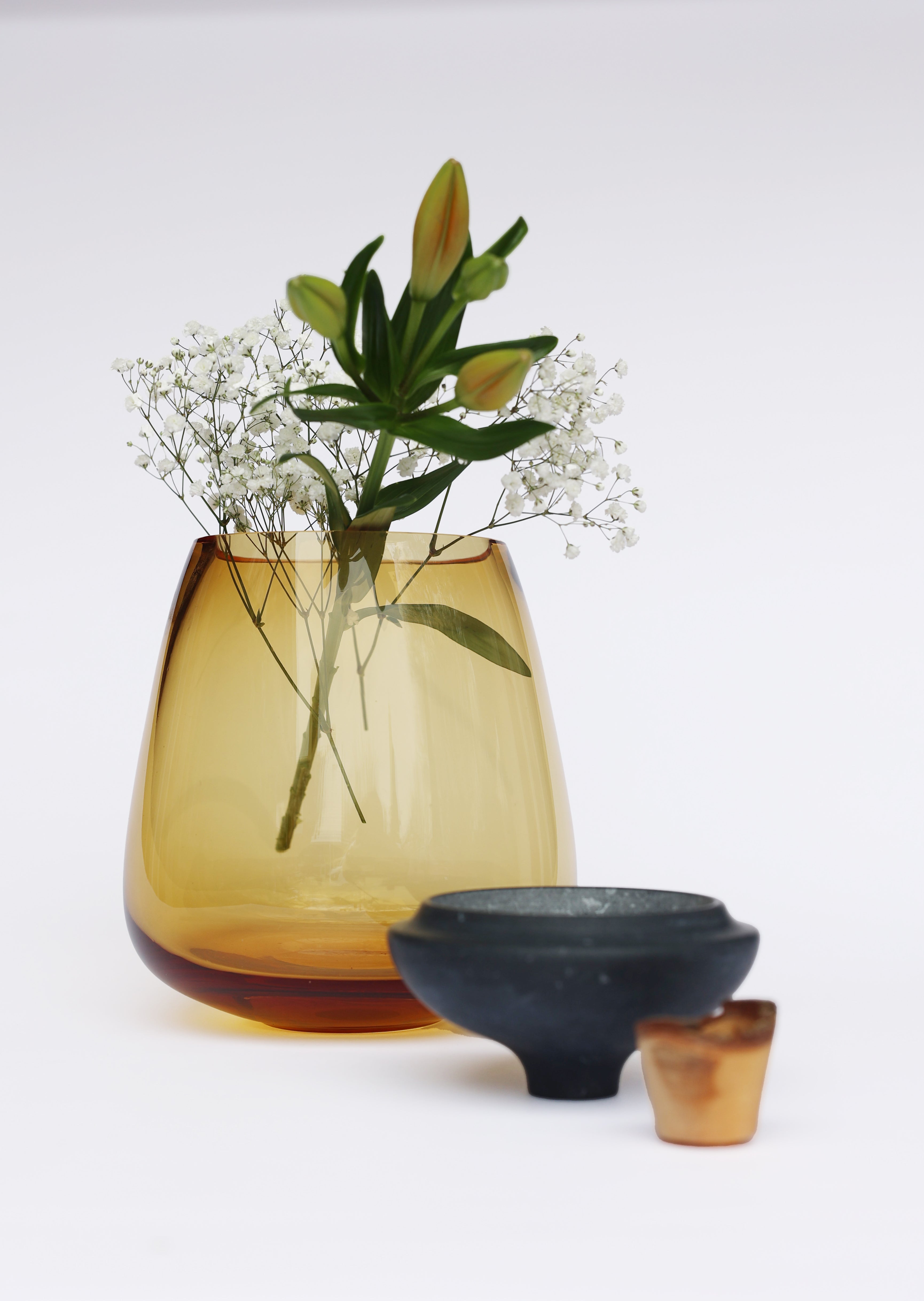 Terra Stacking Vessel Amber in Black Marble unstacked with flower, featuring a striking contrast of textures and materials in a sculptural form.