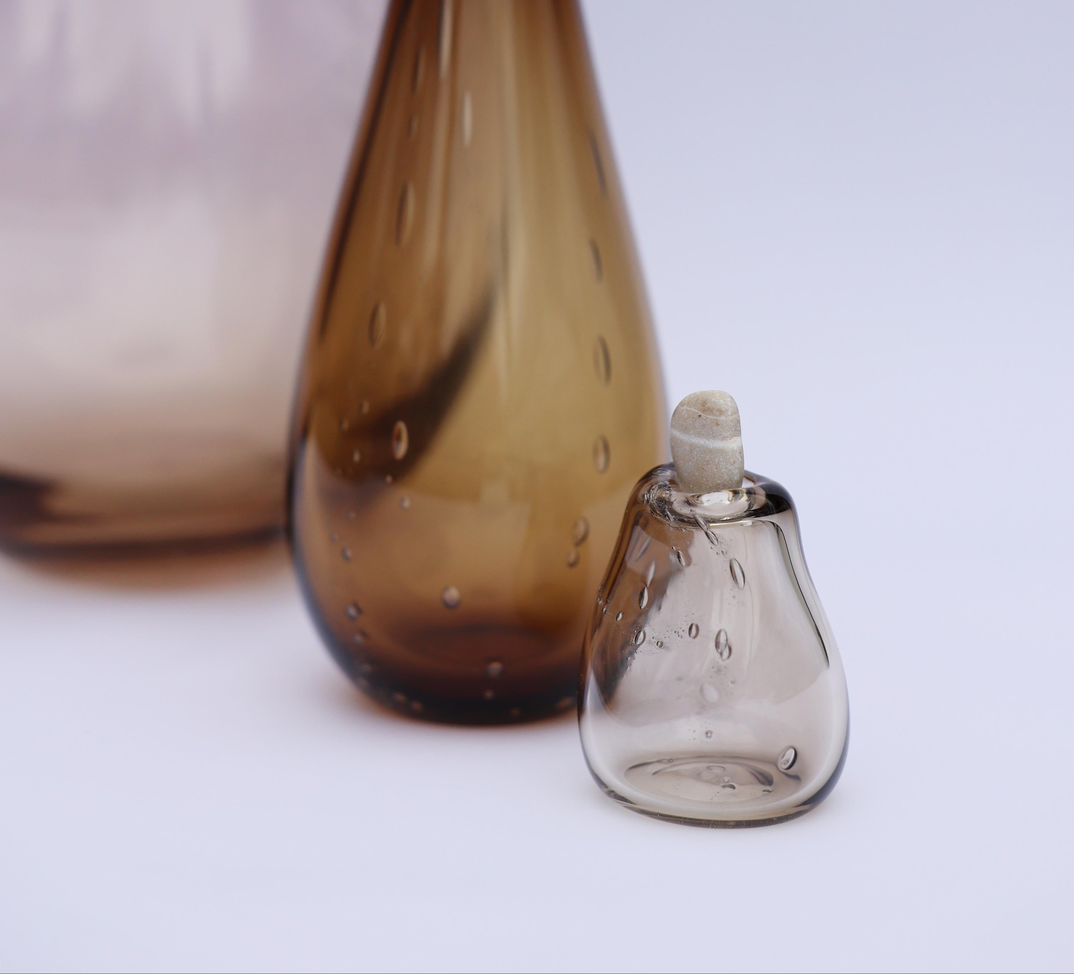 Two glass bottles, one large and brown, the other small and clear, on a light background.
